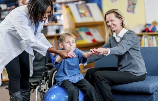 Special Needs Boy little boy with a disability doing therapy on yoga ball
